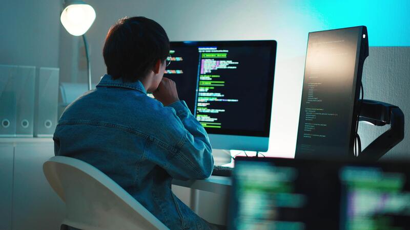 Software developer debugging code on screen - Software developer focused on debugging code with multi screen ...